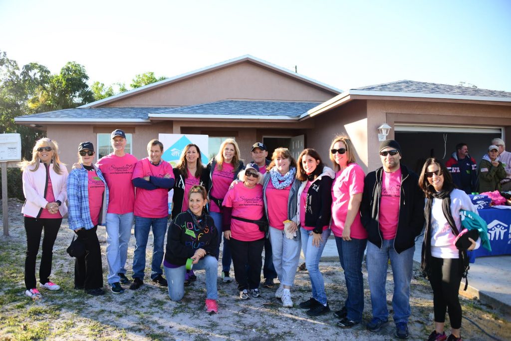 Signature Gives Back team posing in front of a house